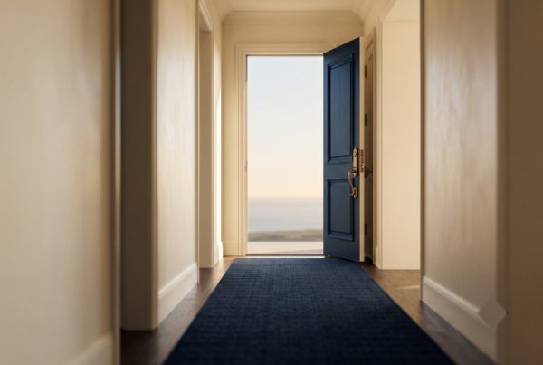 Open door at the end of a corridor looking out to a bright horizon